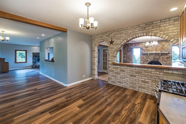 kitchen featuring a stone fireplace, dark wood-type flooring, brick wall, and stainless steel range oven