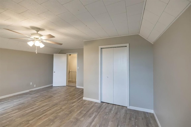 unfurnished bedroom with ceiling fan, light hardwood / wood-style floors, lofted ceiling, and a closet