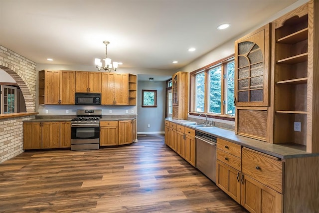 kitchen featuring sink, dark wood-type flooring, stainless steel appliances, brick wall, and pendant lighting