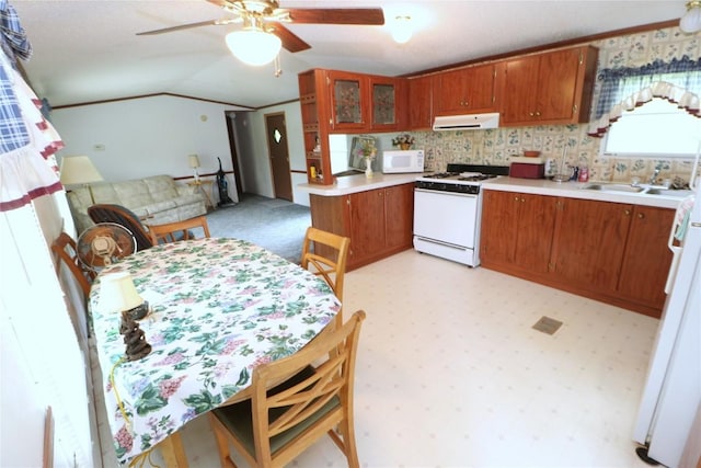 22080 Merganser Ln, Cochranton, PA 16314 - kitchen with white appliances, under cabinet range hood, brown cabinetry, light countertops, and lofted ceiling