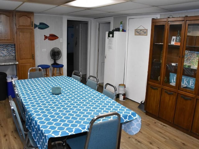 dining area with a drop ceiling and light hardwood / wood-style floors