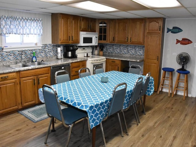 kitchen featuring a drop ceiling, white appliances, backsplash, sink, and light wood-type flooring