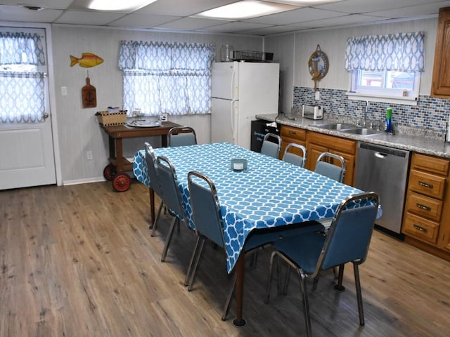 interior space with a paneled ceiling, plenty of natural light, sink, and light hardwood / wood-style flooring