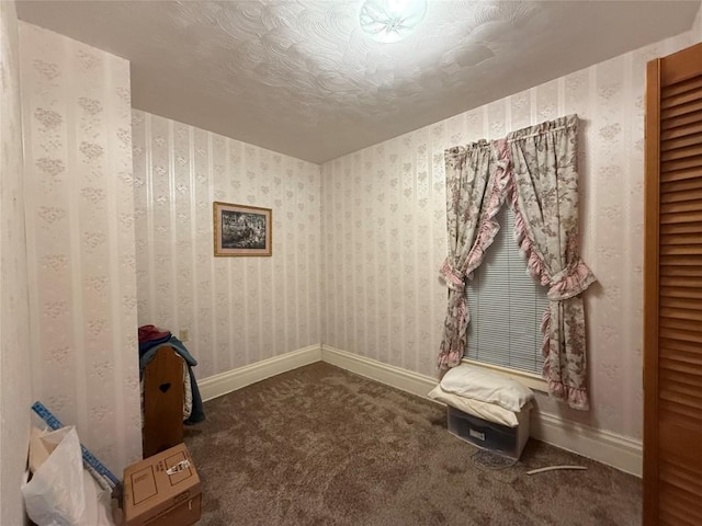 interior space featuring carpet, a textured ceiling, baseboards, and wallpapered walls