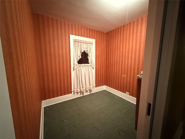 empty room with dark carpet, baseboards, and wallpapered walls