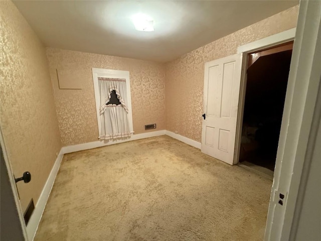 carpeted empty room featuring a textured wall and baseboards