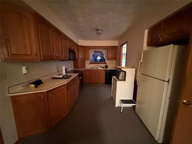 kitchen with a sink, black appliances, light countertops, and brown cabinets