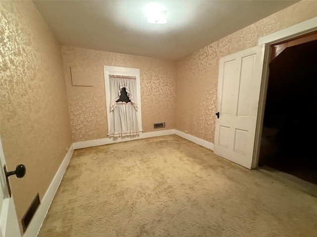 carpeted empty room featuring a textured wall, visible vents, and baseboards