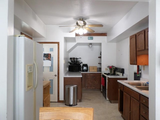 kitchen featuring black microwave, a sink, range with gas stovetop, light countertops, and white fridge with ice dispenser