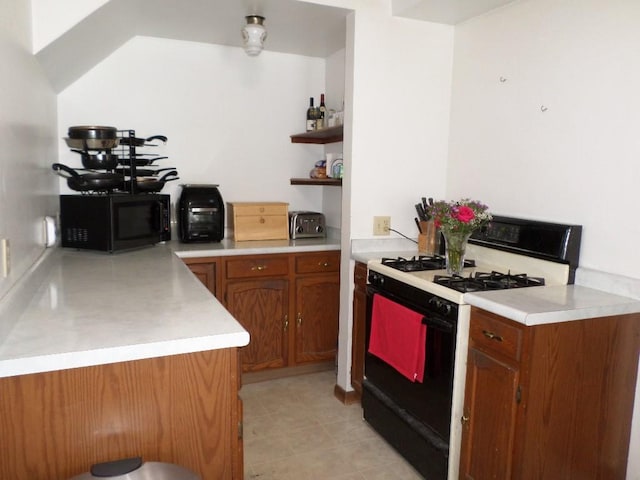 kitchen featuring brown cabinets, gas stove, black microwave, and light countertops