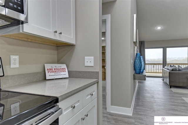 kitchen with light hardwood / wood-style flooring, white cabinetry, and electric range