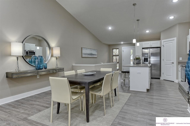 dining space with lofted ceiling, sink, and light hardwood / wood-style floors