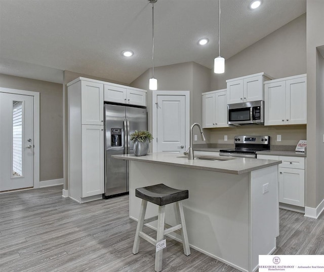 kitchen featuring white cabinets, light hardwood / wood-style flooring, decorative light fixtures, and appliances with stainless steel finishes