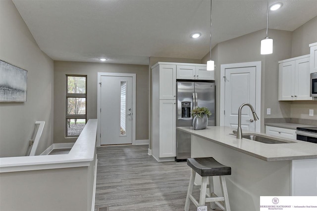 kitchen featuring lofted ceiling, sink, light wood-type flooring, and white cabinets