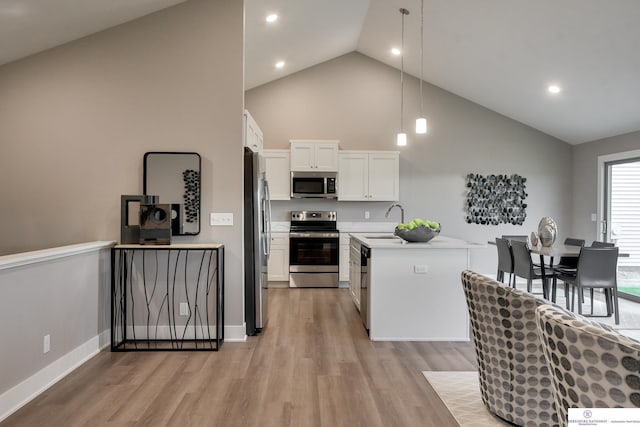 kitchen featuring white cabinets, decorative light fixtures, stainless steel appliances, and light hardwood / wood-style flooring