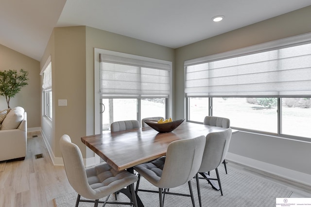dining area with light hardwood / wood-style floors, vaulted ceiling, and a wealth of natural light