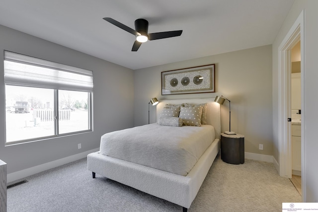 bedroom featuring light carpet, connected bathroom, and ceiling fan
