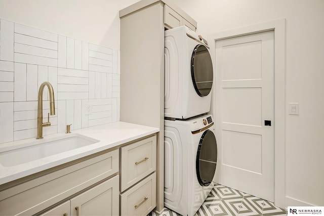 laundry room featuring cabinets, stacked washer / dryer, and sink