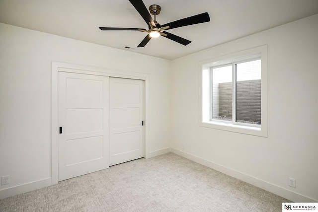 unfurnished bedroom with ceiling fan, light colored carpet, and a closet