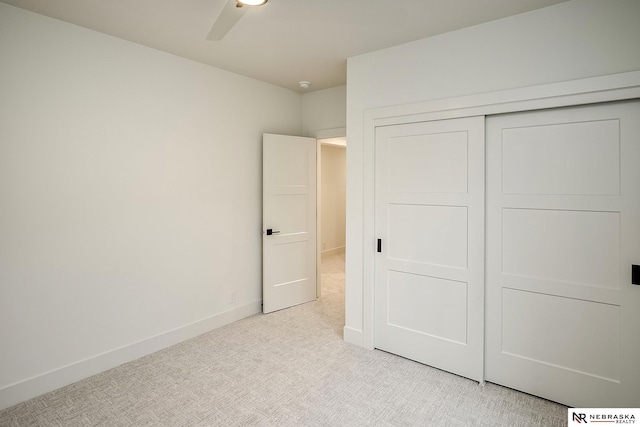 unfurnished bedroom with a closet, light colored carpet, and ceiling fan