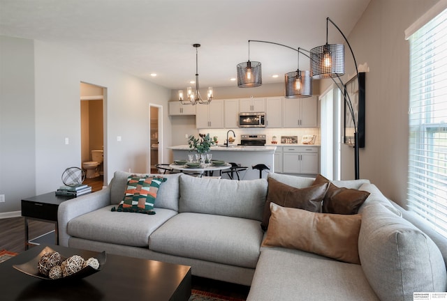 living room with hardwood / wood-style floors, sink, and a notable chandelier