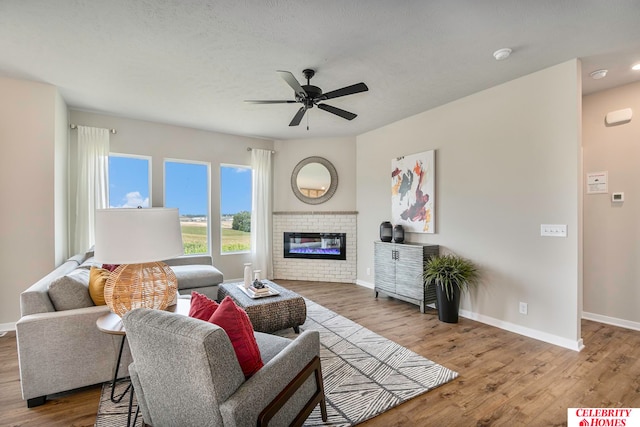 living room featuring a fireplace, ceiling fan, and light hardwood / wood-style flooring