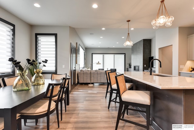 kitchen featuring hanging light fixtures, a kitchen breakfast bar, sink, light hardwood / wood-style flooring, and a chandelier