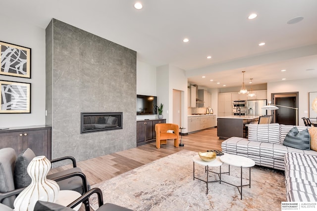 living room with a notable chandelier, light wood-type flooring, and a fireplace