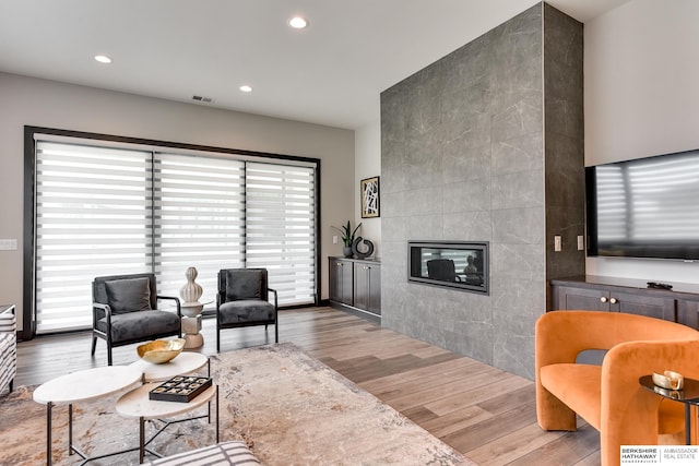 living room featuring a tiled fireplace and light hardwood / wood-style floors