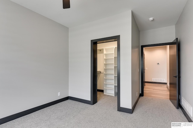 unfurnished bedroom with light carpet, a spacious closet, and a closet