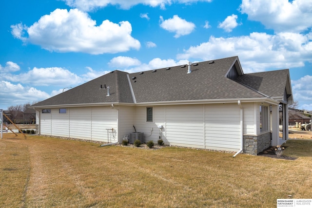 rear view of house featuring central air condition unit and a lawn