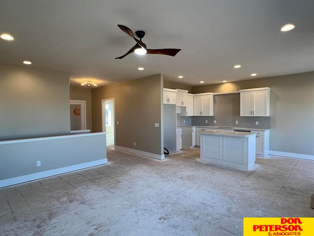 kitchen featuring ceiling fan, white cabinets, light tile flooring, tasteful backsplash, and a center island