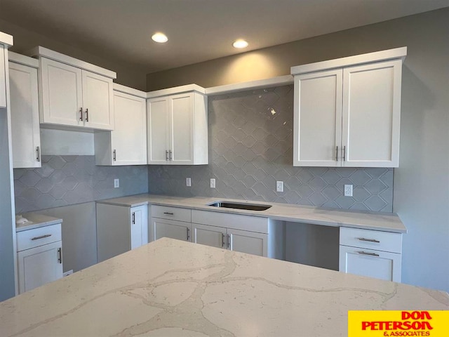 kitchen with white cabinets, backsplash, and light stone counters