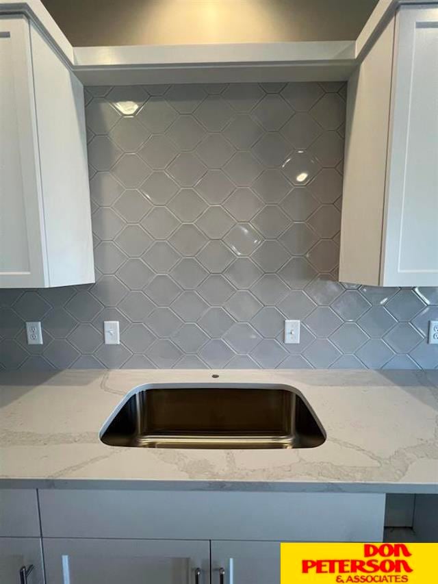 kitchen with light stone countertops, backsplash, and white cabinets