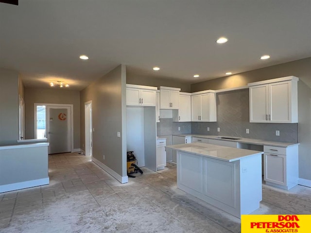 kitchen featuring light stone countertops, white cabinetry, backsplash, light tile floors, and a kitchen island