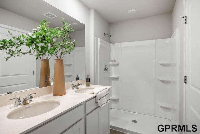 bathroom with walk in shower and dual vanity