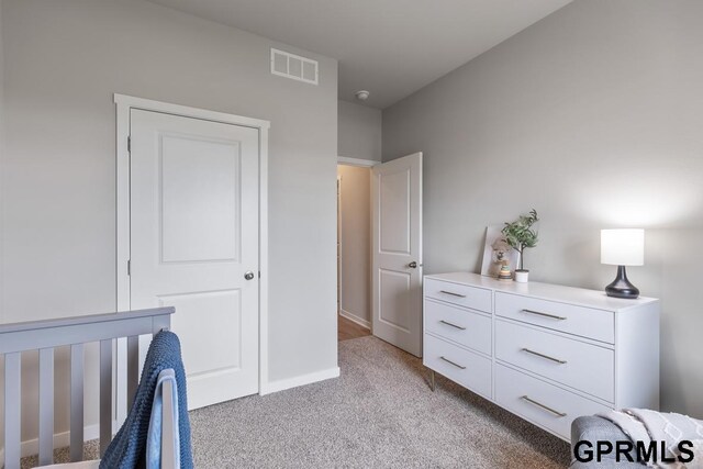 bedroom featuring a nursery area and light colored carpet