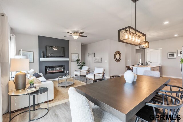 dining area featuring ceiling fan with notable chandelier and light hardwood / wood-style floors