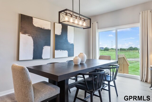 dining area with light hardwood / wood-style floors and a notable chandelier