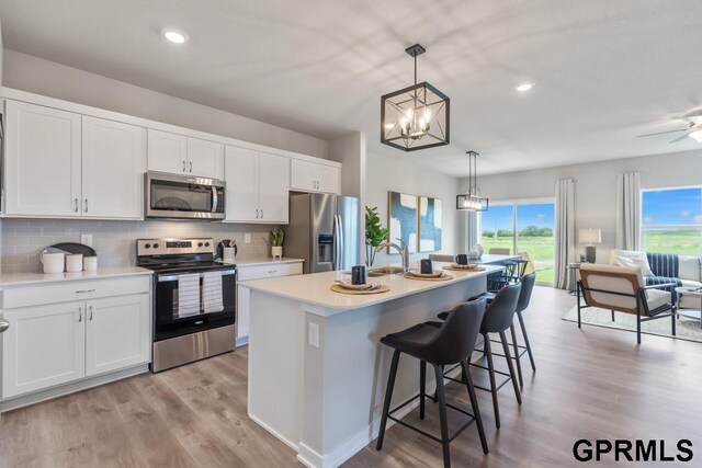 kitchen with stainless steel appliances, light hardwood / wood-style floors, and white cabinets