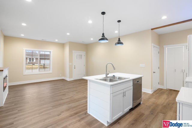 kitchen featuring hanging light fixtures, light hardwood / wood-style floors, sink, an island with sink, and stainless steel dishwasher