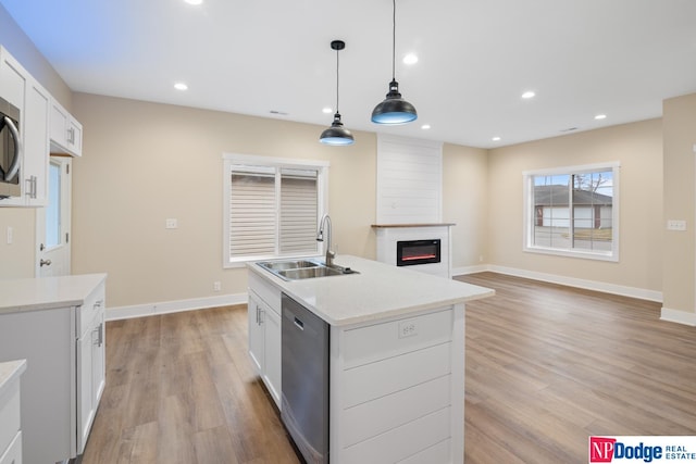 kitchen featuring light wood-type flooring, decorative light fixtures, sink, white cabinetry, and a large fireplace