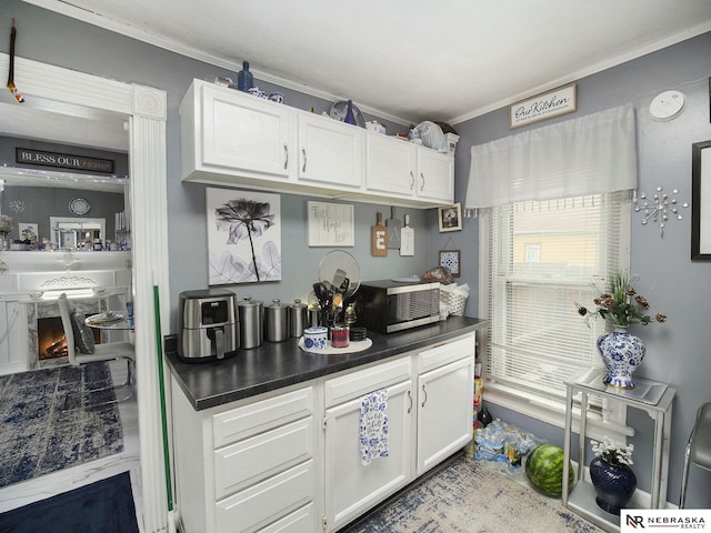 kitchen featuring white cabinets, light tile floors, and crown molding