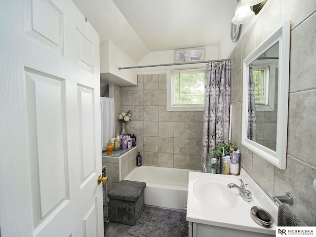 bathroom with tile walls, shower / bath combo, and vanity with extensive cabinet space