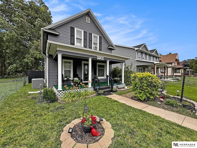 view of front of property featuring central AC, a front yard, and a porch