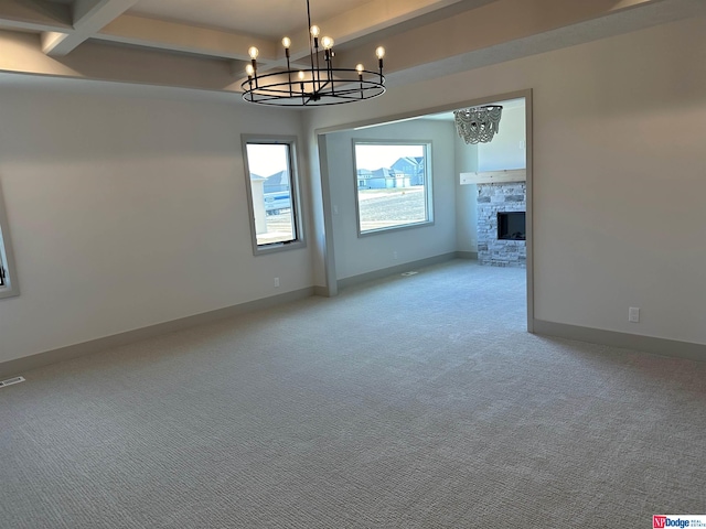 unfurnished living room with beam ceiling, light colored carpet, a fireplace, and a chandelier