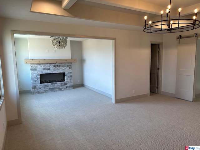 unfurnished living room featuring light carpet, a barn door, a fireplace, beamed ceiling, and a notable chandelier