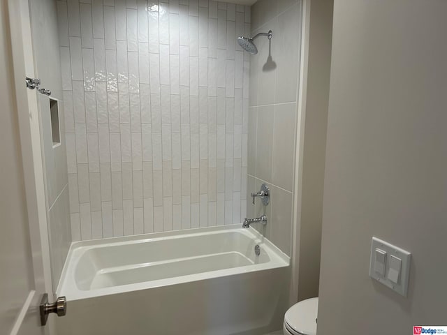 bathroom featuring toilet and tiled shower / bath