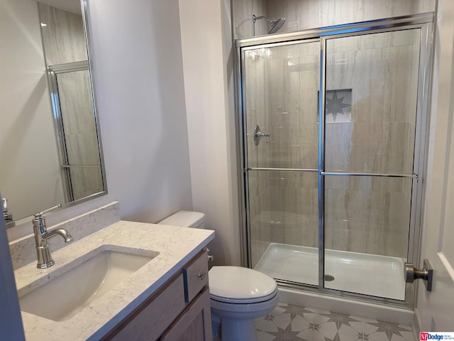 bathroom featuring vanity, a shower with shower door, and toilet