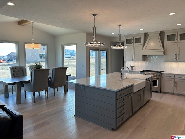 kitchen featuring decorative light fixtures, sink, premium range hood, and tasteful backsplash